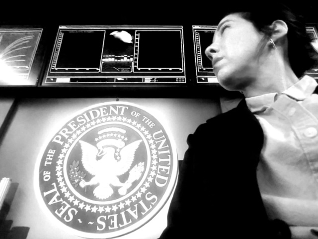 Man looking at screens with the U.S. presidential seal projected below.