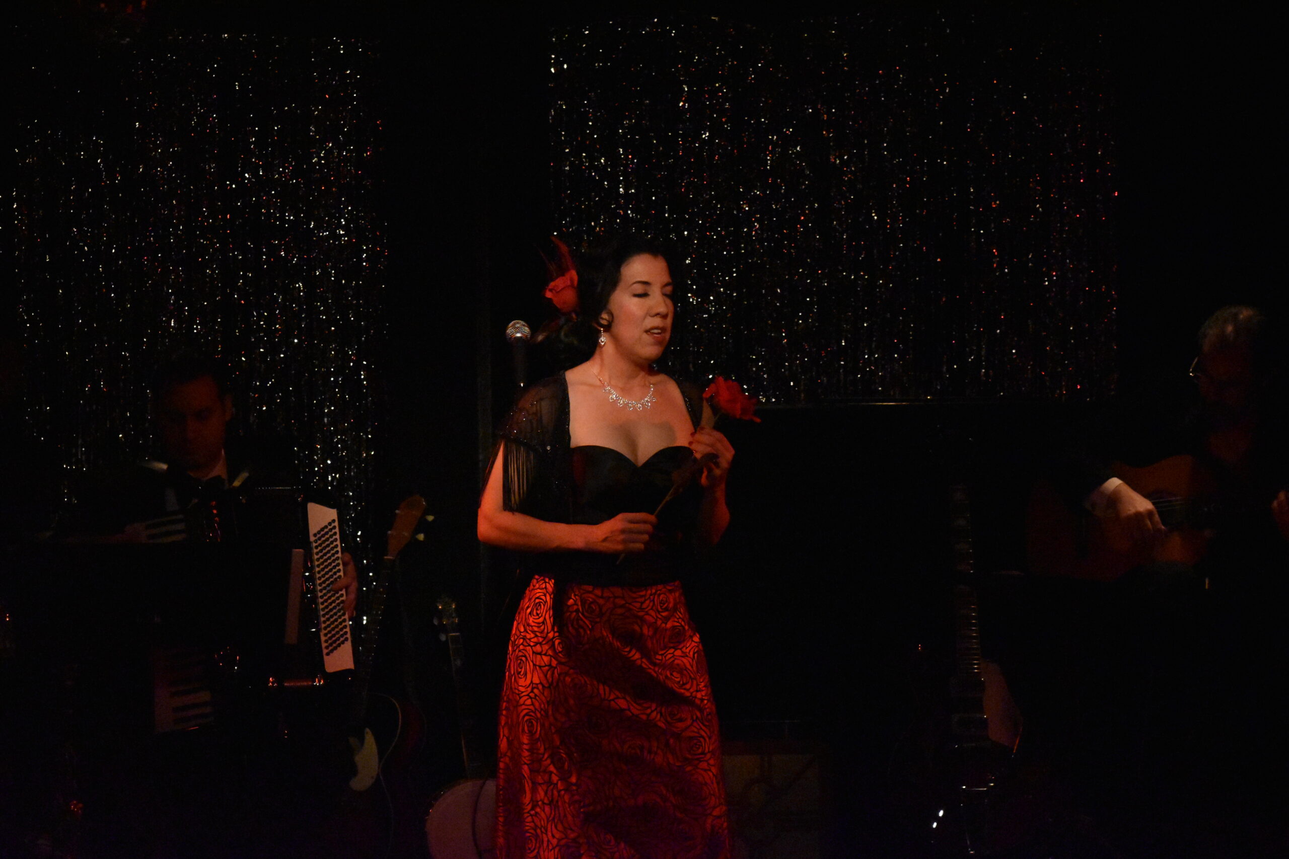 Woman in elegant red and black evening gown performing on stage.