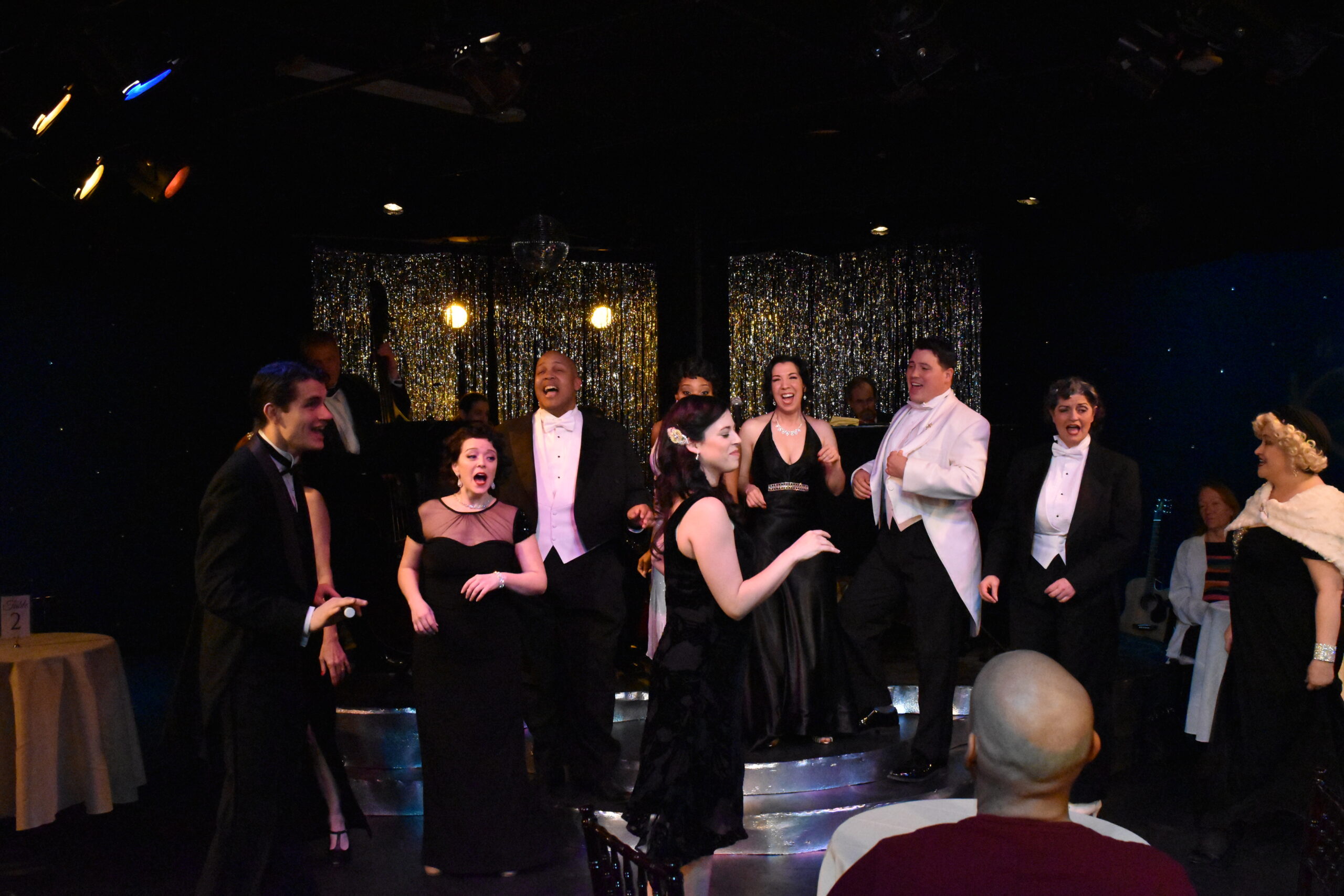 A group of performers on stage during a dramatic scene.