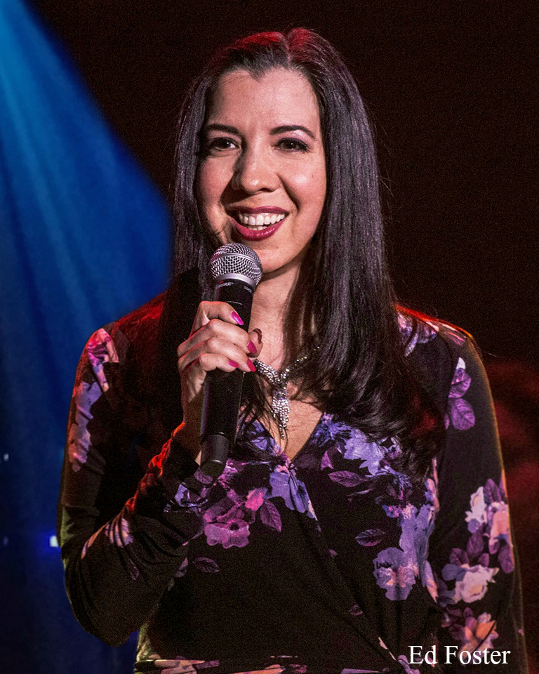Woman smiling and holding a microphone on stage.