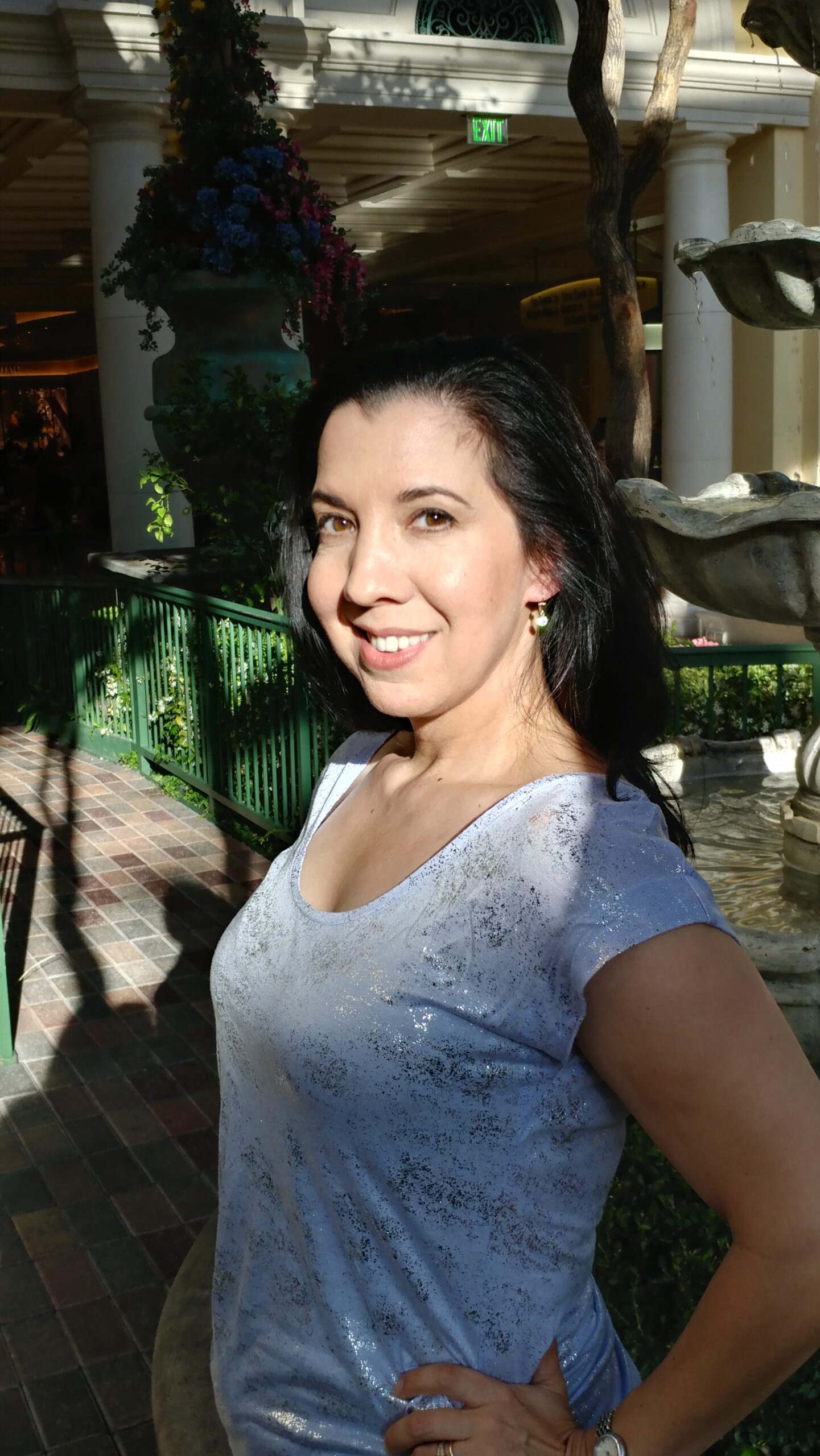 Woman smiling outdoors in a sunlit area.