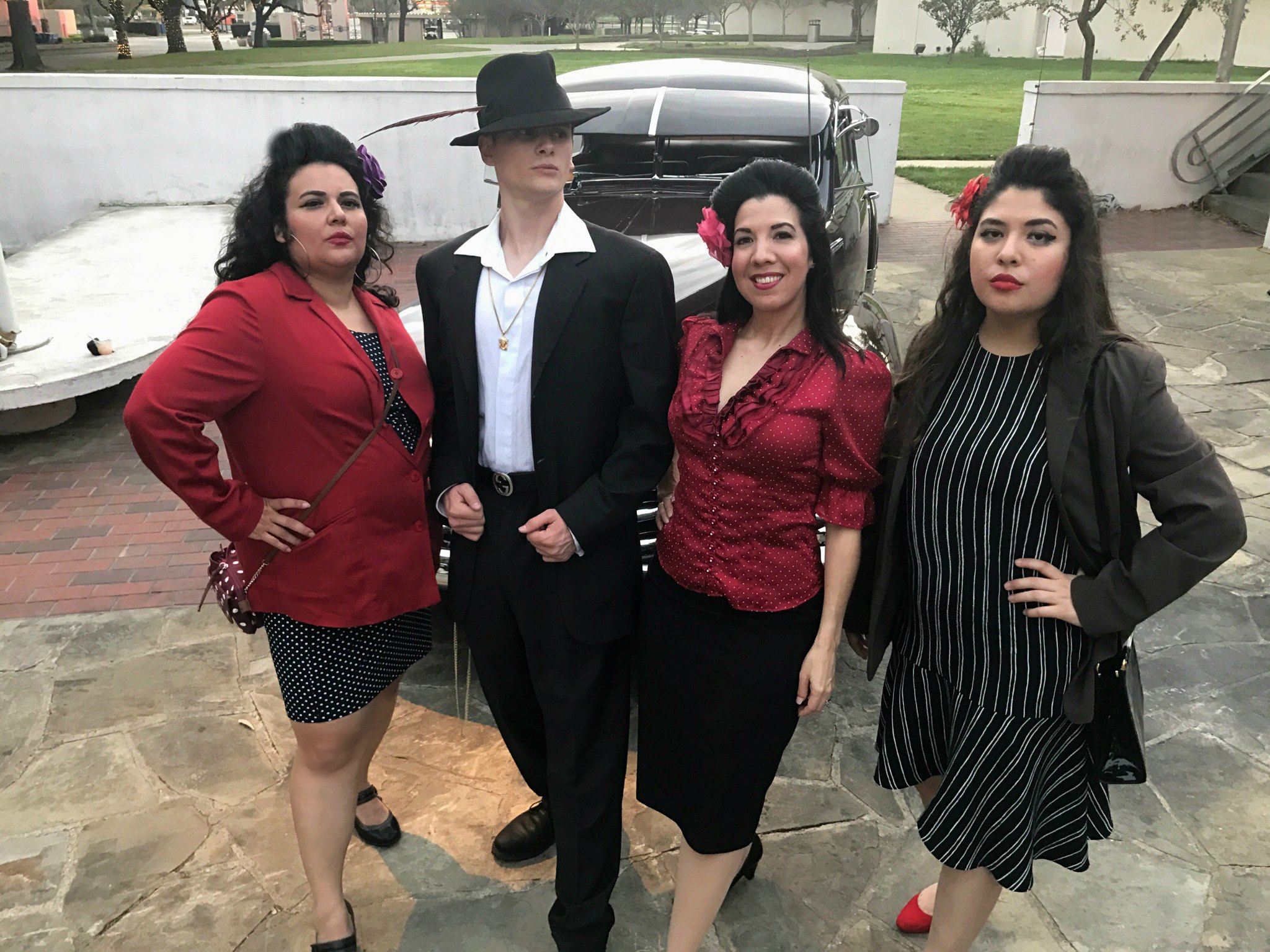 Four women posing outdoors in formal and casual attire.