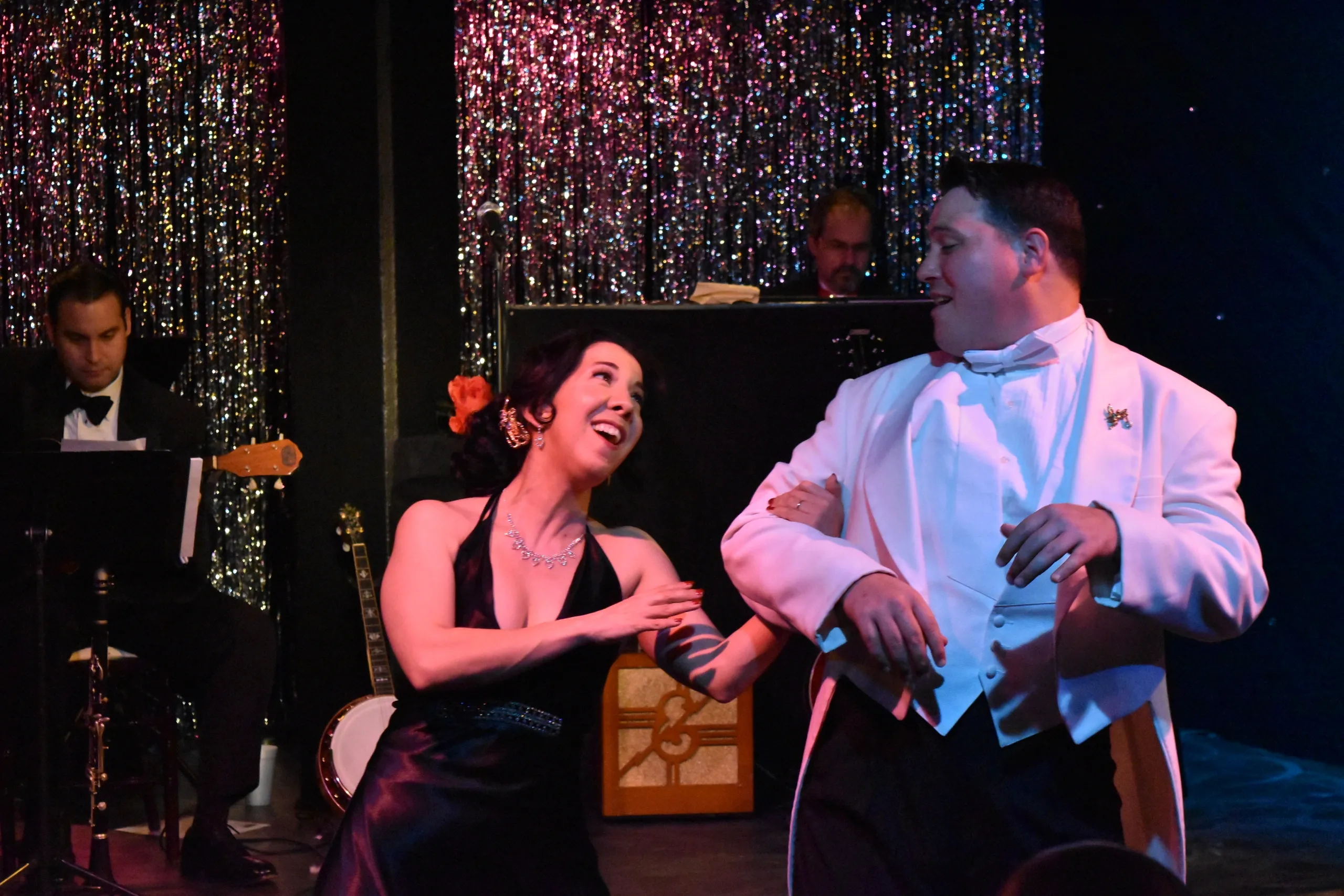 A couple joyfully dancing together on a glittering stage.