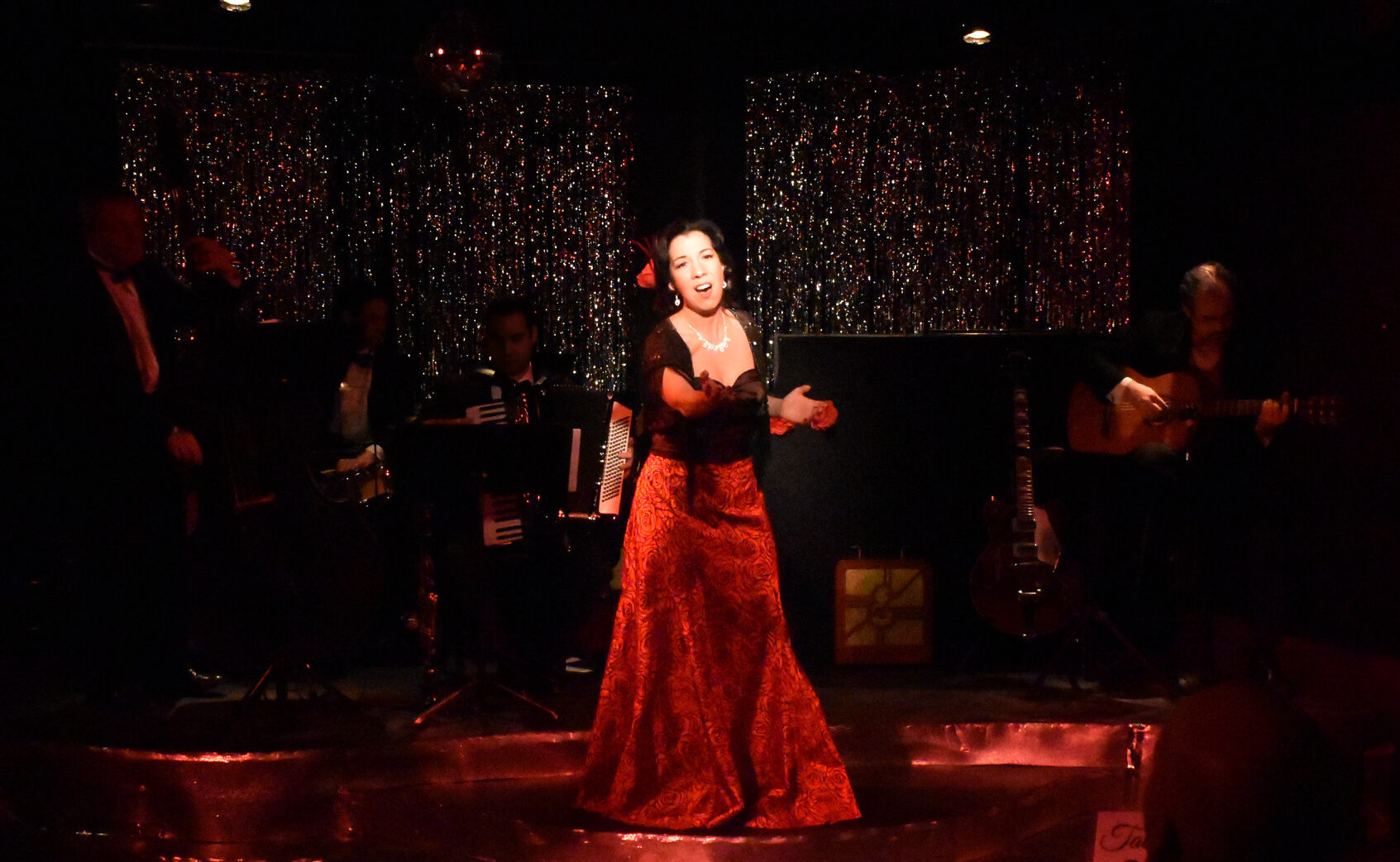 A woman in a red dress passionately performing flamenco on stage.