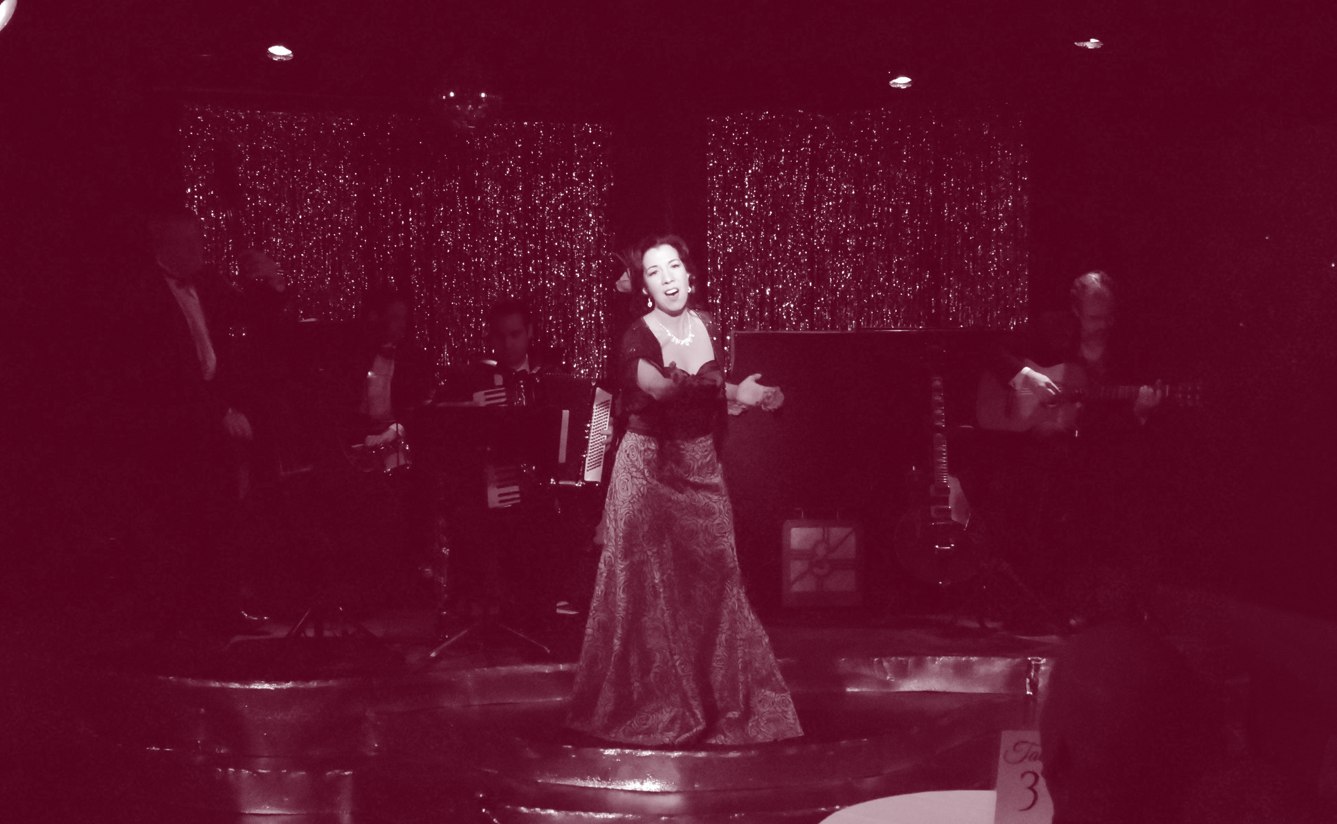A woman singing passionately on stage in a long dress.